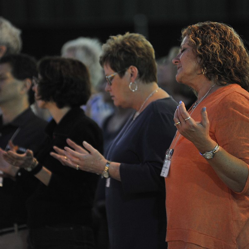adults in prayer at power and purpose conference, 2015