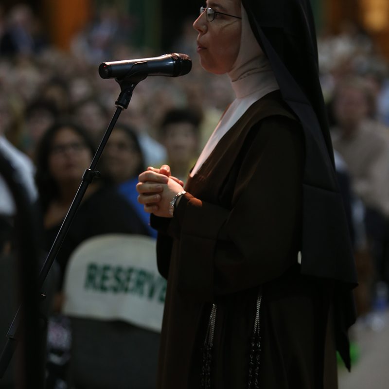 Nun at microphone in the fieldhouse
