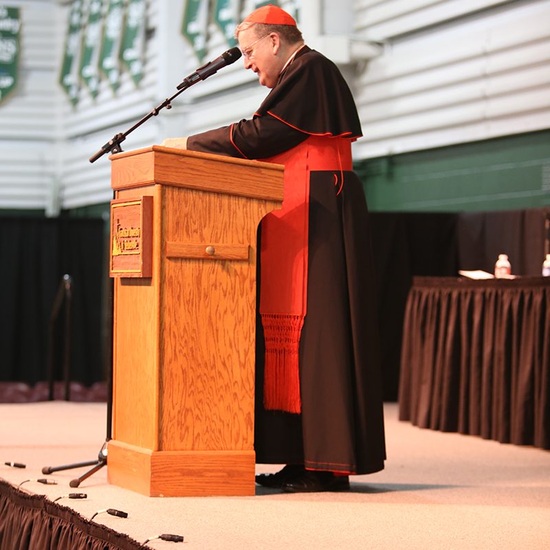 Cardinal at podium in Franciscan Fieldhouse