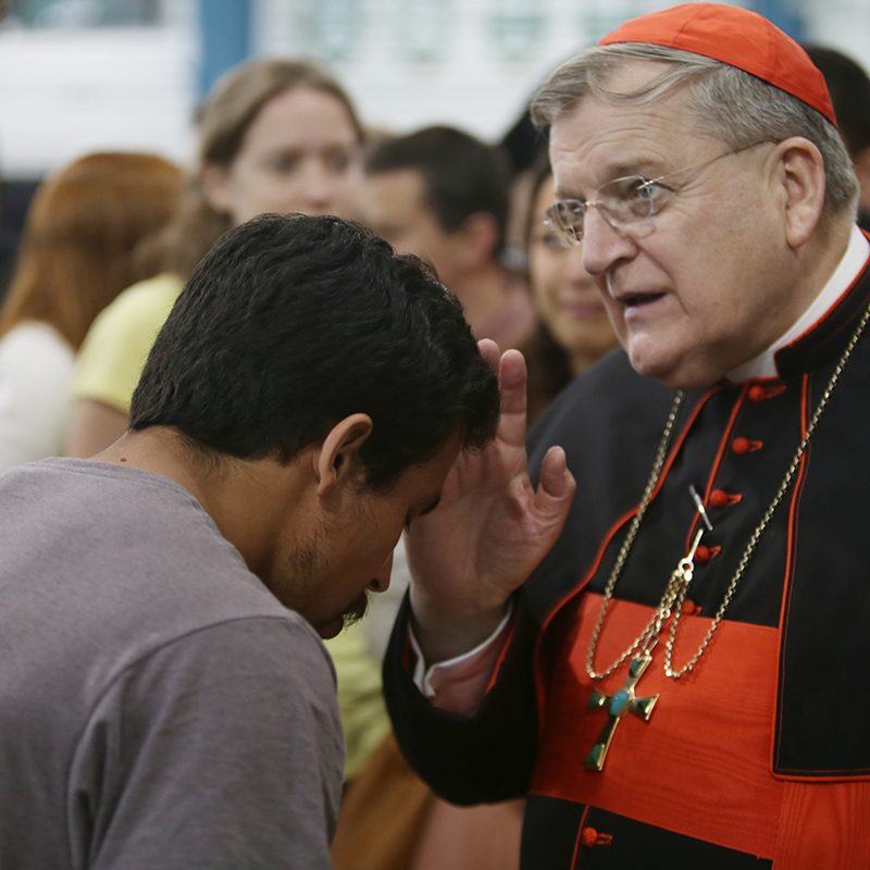 Cardinal saying prayer over man