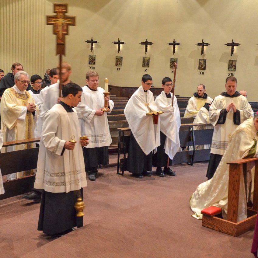 bishop montforton kneeling in front of the alter in christ the king chapel