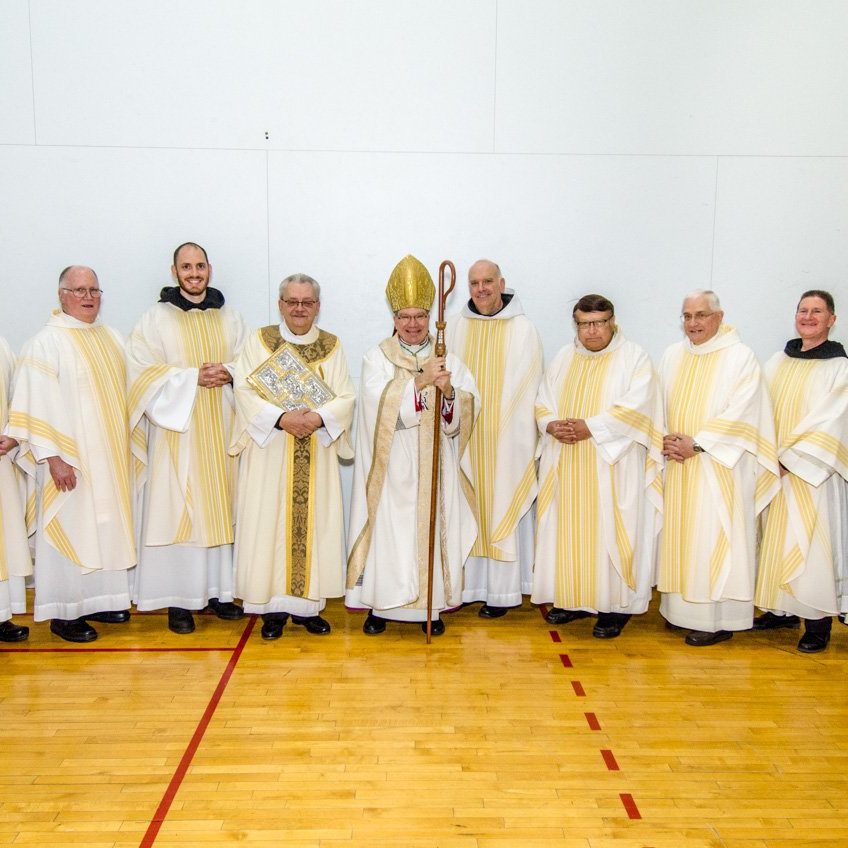 priests gathered around the bishop for a photo