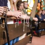 people with rosaries in christ the king chapel