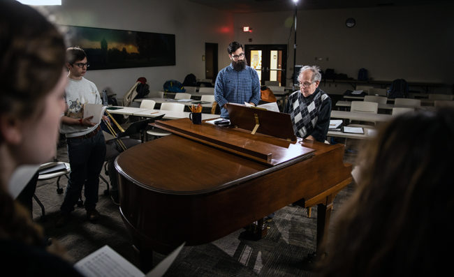 professor playing piano for students