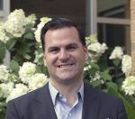 image of Joe Wallce the new Director of Community relations standing in front of flowers.