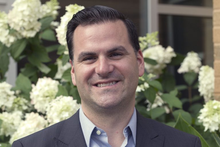 image of Joe Wallce the new Director of Community relations standing in front of flowers.