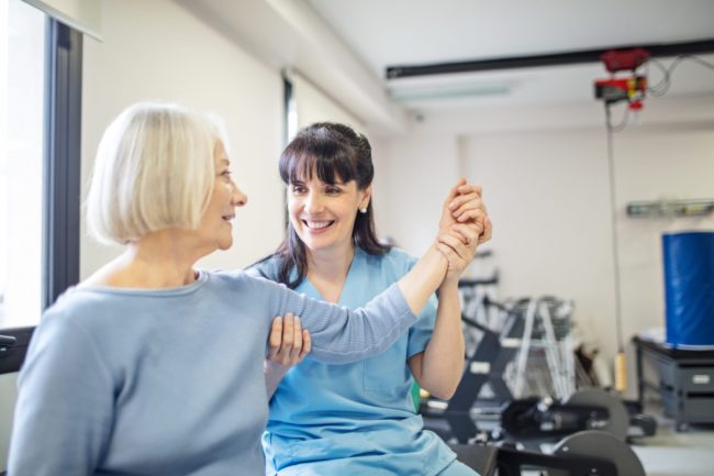 Nurse assisting senior woman with hand exercise