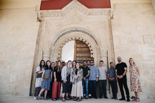 A group photo in front of a white arched doorway in Iraq.