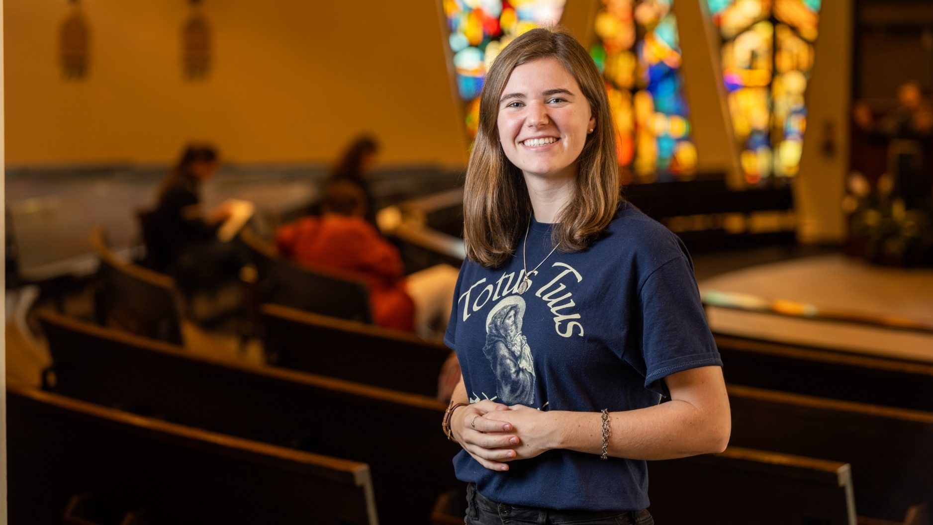 student with household shirt smiling in the Christ the King chapel