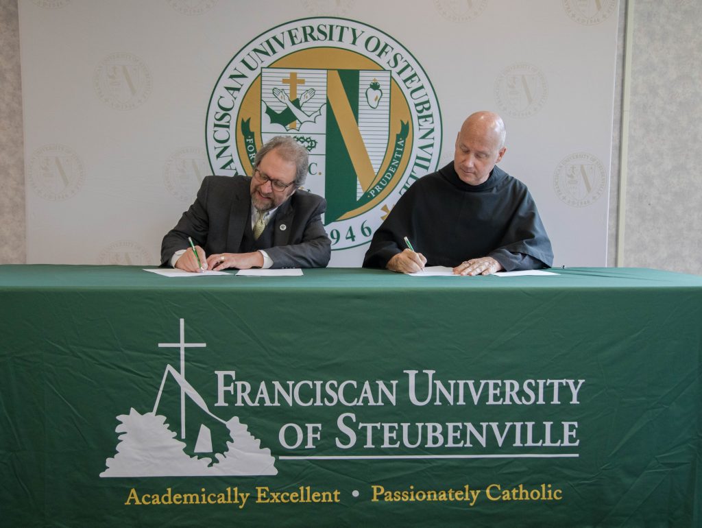 Dale Ahlquist, president of the Society of G.K. Chesterton, and Father Dave Pivonka, TOR, president of Franciscan University of Steubenville, signed the agreement between the Chesterton Schools Network and Franciscan University on April 8, 2022.
