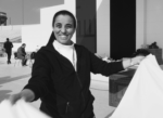 Black and white photo of a nun outside with a table cloth in her hand.