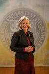 Dr. Jacqueline Leonard standing in front of a university seal.