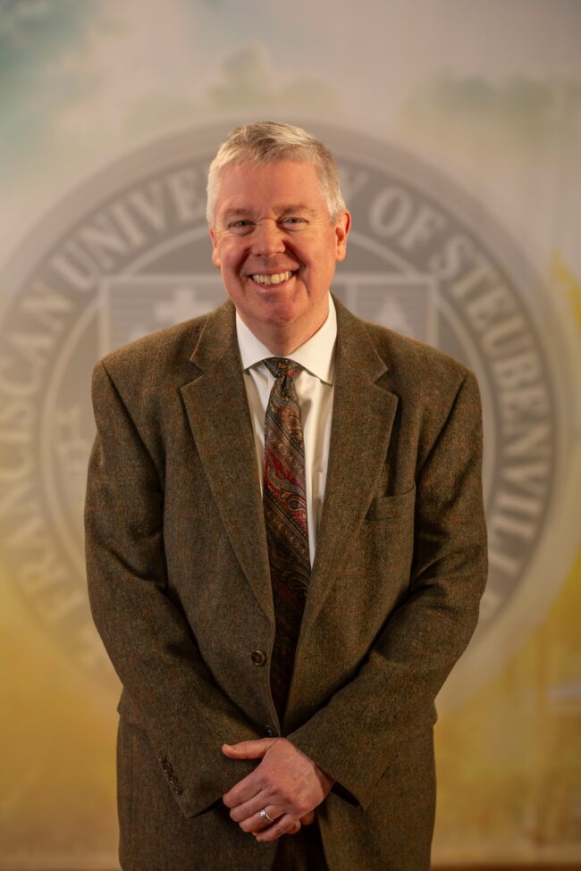 Dr. Matthew O’Brien standing in front of a university seal.