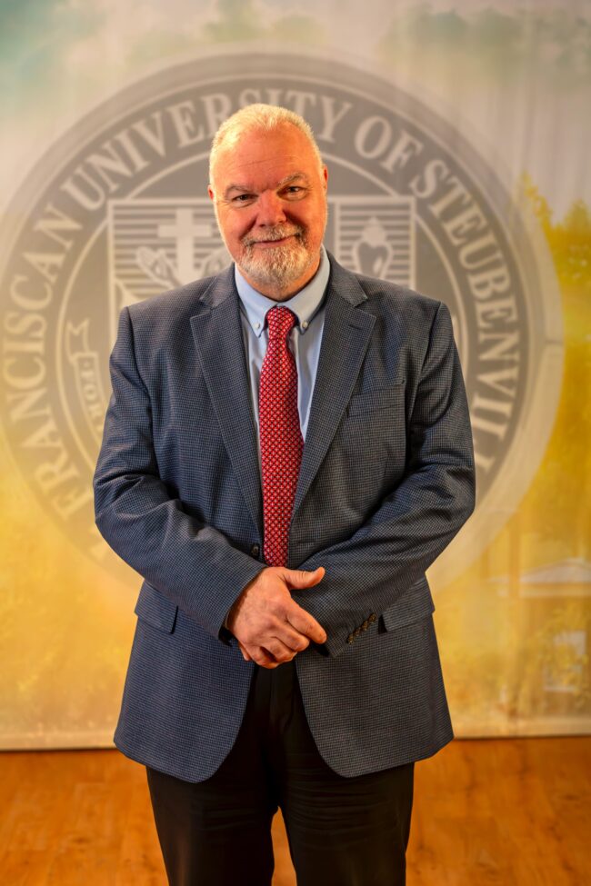 To Web – Dr. Petroc Willey FEB2025 –6 Dr. Petroc Willey standing in front of a university seal.