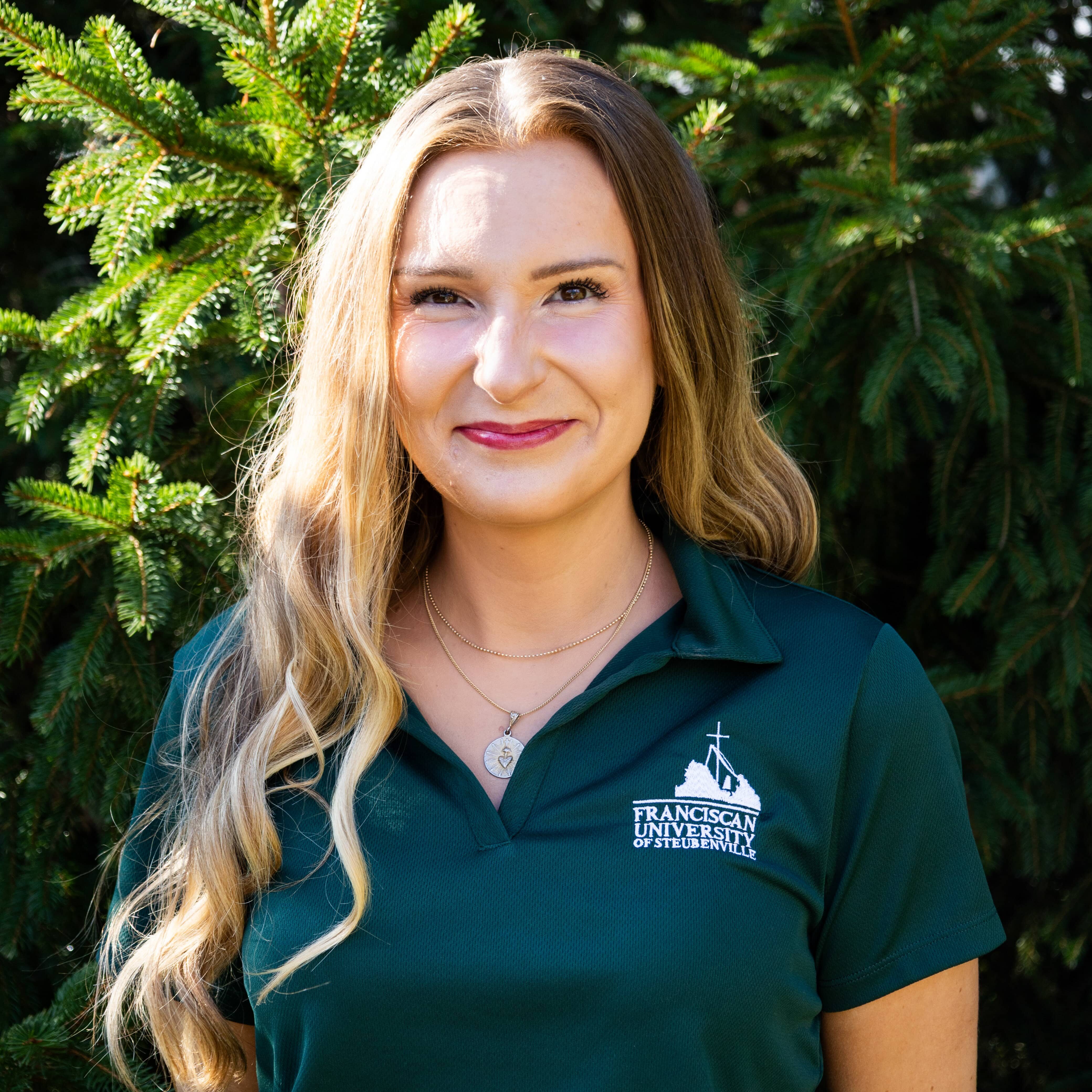 Megan Case Admission Counselor Outdoor portrait of Megan Case wearing a green polo embroidered with the Franciscan University of Steubenville logo.