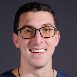 John Caliguire with a blue shirt in front of a dark gray background.
