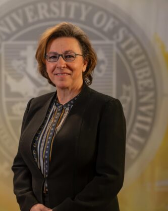 Julie Smith standing in front of a university seal