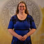 Alicia Boyle standing in front of a university seal.