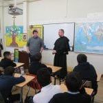 Priest and student teaching class of children