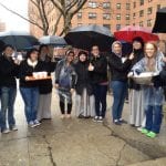 Volunteers standing with umbrellas in the rain