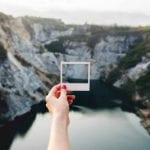 holding Empty polaroid frame over mountain lake