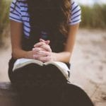 folded hands on book