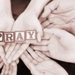 hands holding blocks that say pray