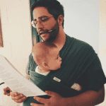 man working while holding child
