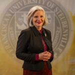 Dr. Jacqueline Leonard standing in front of a university seal.