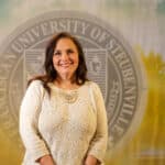Nicole Hough standing in front of a college seal.