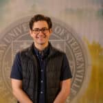 Nick Riccardi standing in front of a college seal.