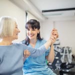 Nurse assisting senior woman with hand exercise