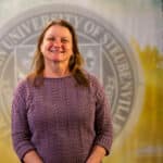 Denise Lombard standing in front of a university seal.