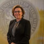 Julie Smith standing in front of a university seal