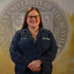 Tanya Dillion standing in front of a university seal.